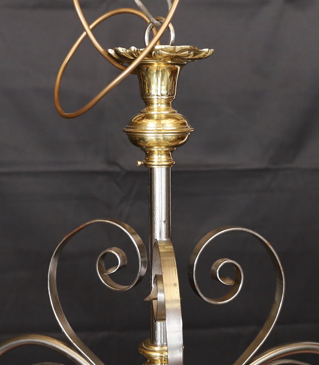 An English Arts & Crafts wrought iron brass and copper three light electrolier with pink tinted opaque glass shades, height 60cm. width 66cm